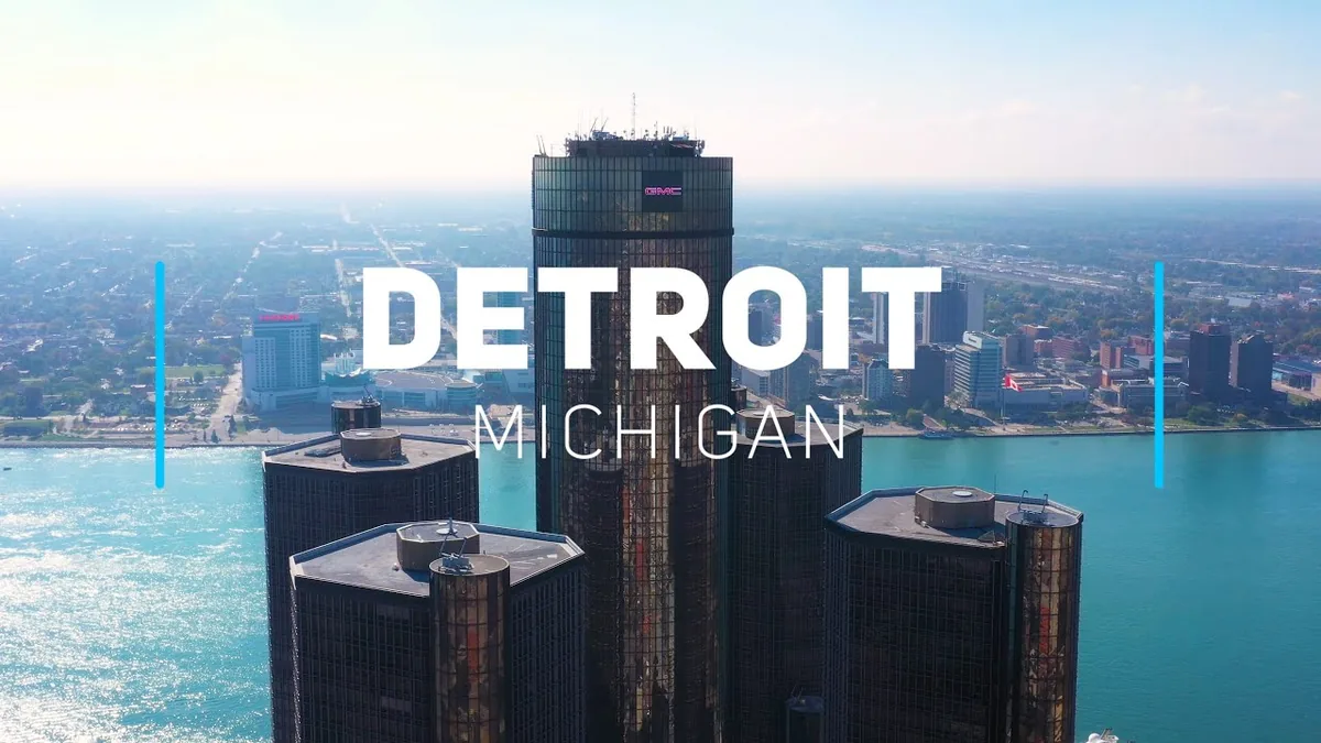 Aerial view of the GM Renaissance Center towers on the Detroit riverfront, with the Detroit River and Windsor beyond
