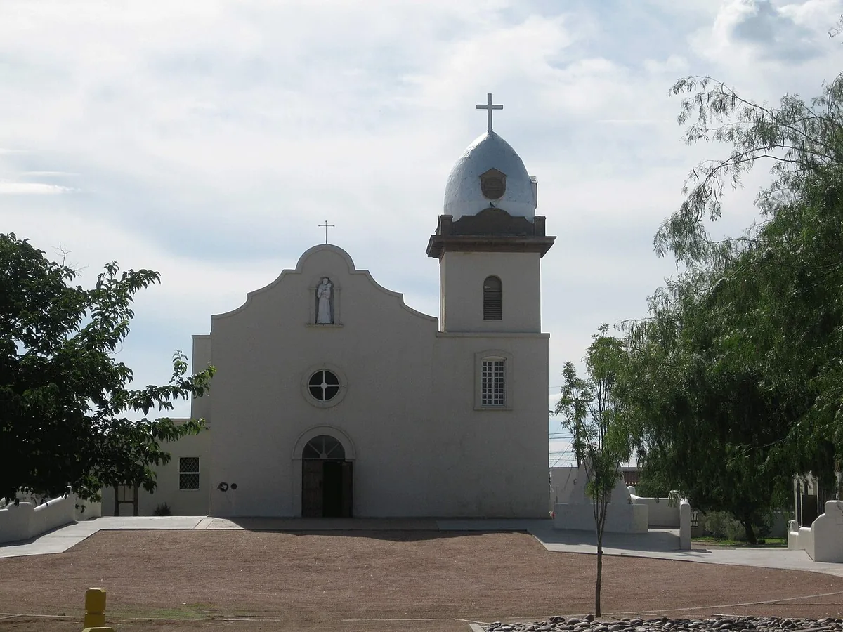 The white adobe facade and domed bell tower of Ysleta Mission in El Paso