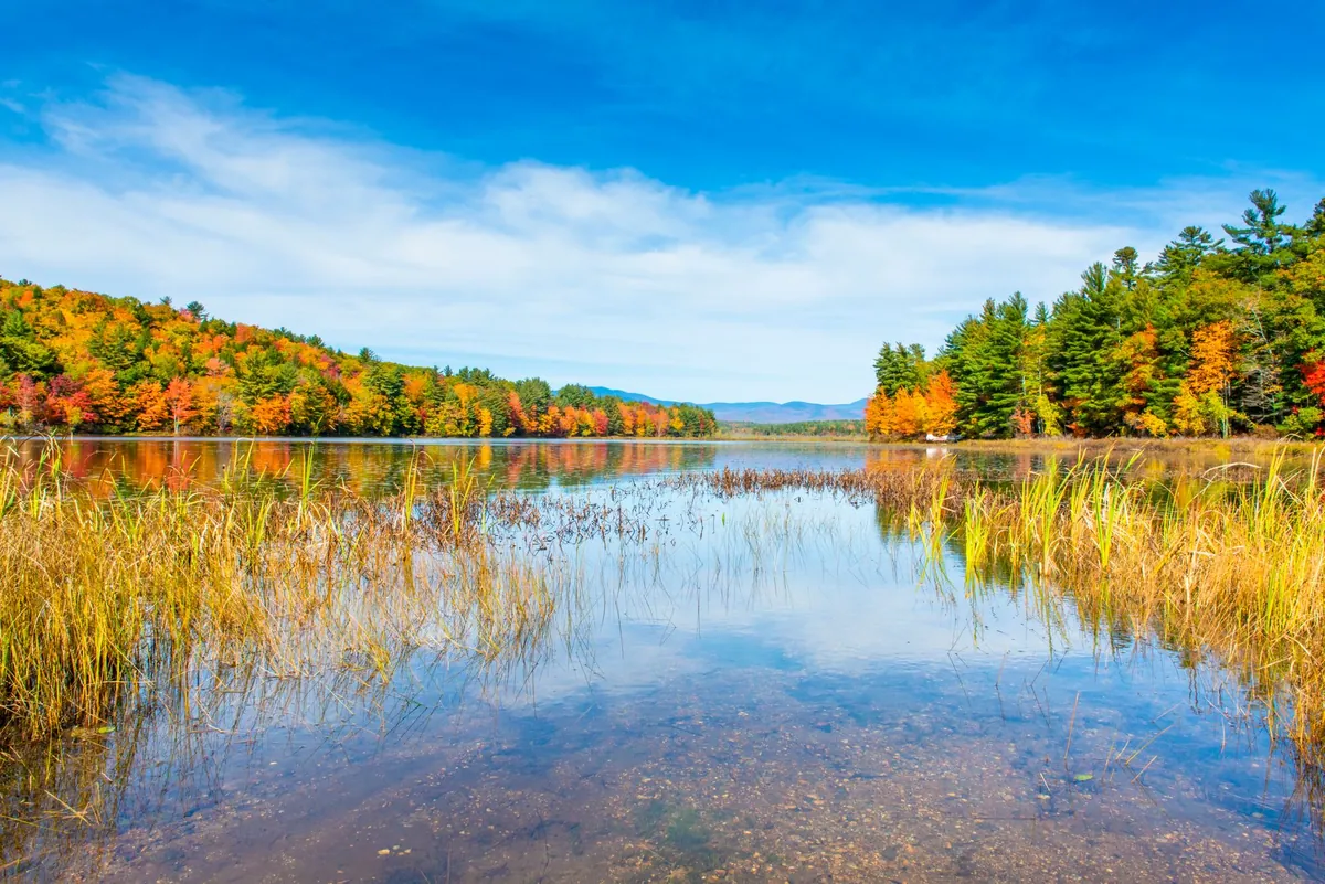 A calm New Hampshire lake reflecting colorful autumn foliage
